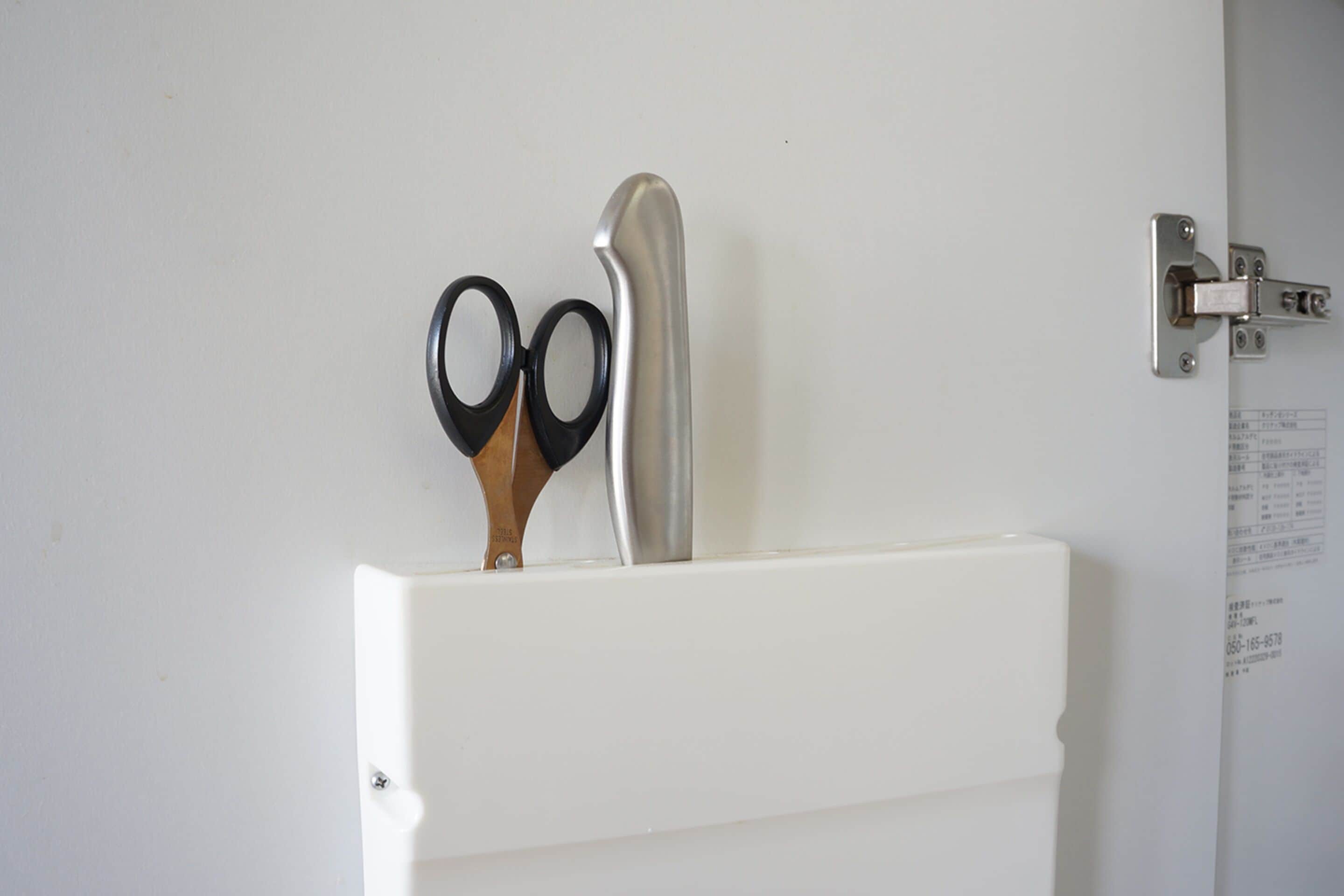 A white door with a metal latch and a pair of scissors mounted on the door frame.