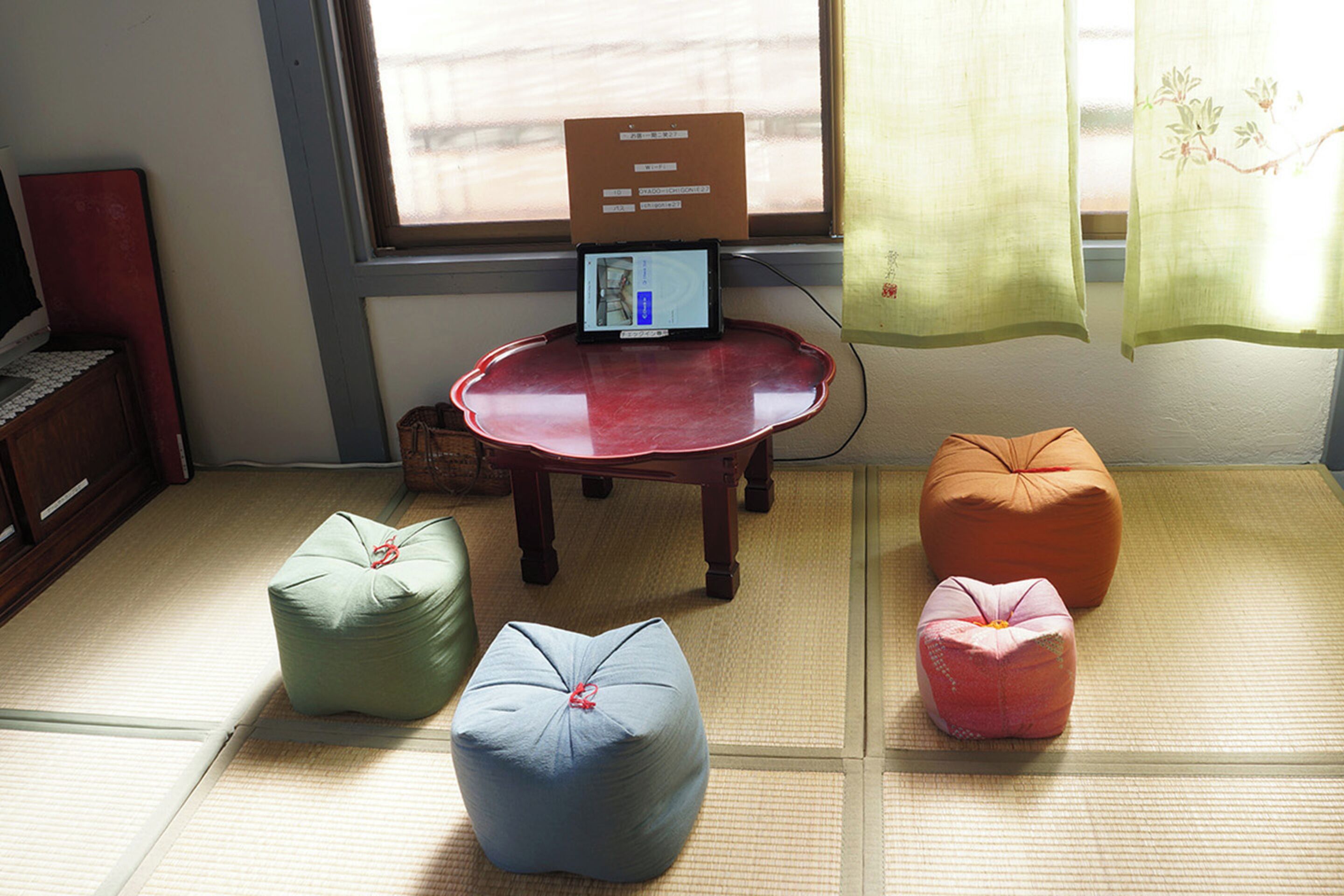 A room with tatami flooring, a wooden table with a laptop, and three bean bags.