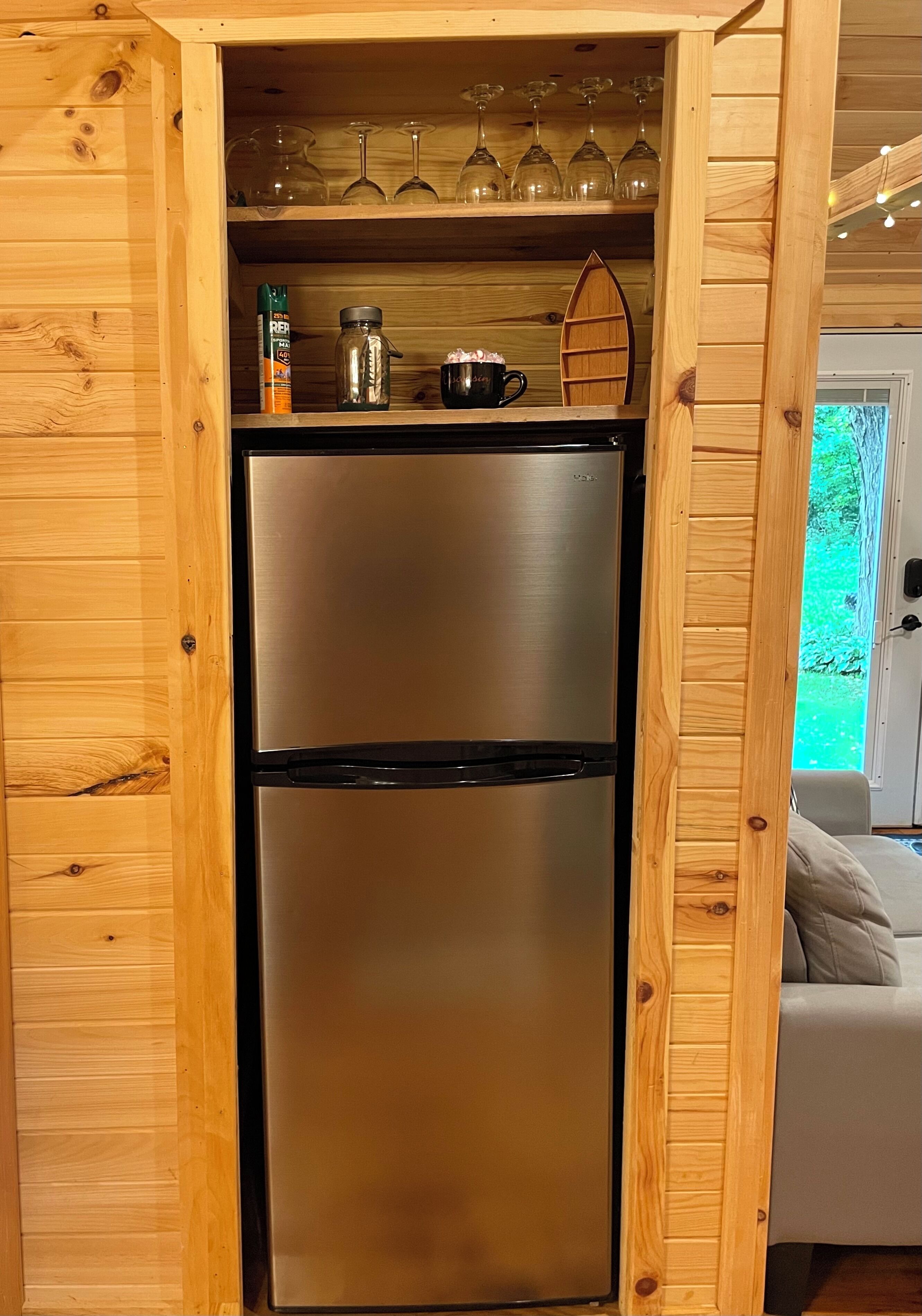 Eine Küche mit Holzrahmen, einem Edelstahl-Kühlschrank, Weingläsern auf der obersten Ablage und einer Kaffeemaschine.
