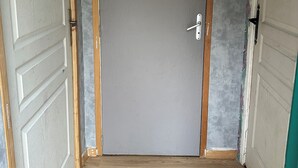 A closed door with a simple handle, flanked by wooden trim and a plain grey wall. - Studio 1 min walk from Châteaubriant castle with complimentary breakfast (Châteaubriant)
