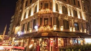 Un edificio histórico con arquitectura ornamentada, varios balcones y una fachada bien iluminada.