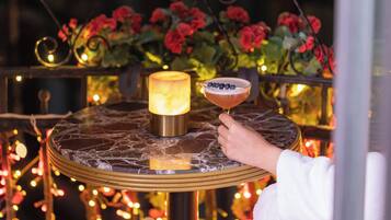 A round table with a marble top, a lit candle, and a cocktail glass with a garnish.