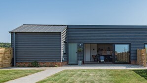 Ein modernes, zweistöckiges Haus mit einer Terrasse und einer Glastür zu einem Essbereich.