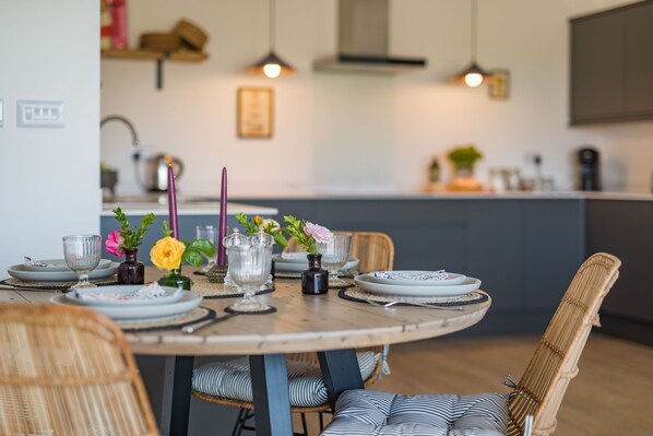 A dining table set with plates, glasses, and a vase with flowers.