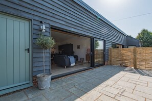 A modern house with a sliding glass door leading to a living area with a sofa and a coffee table.