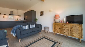 Ein modernes Wohnzimmer mit grauem Sofa, Holzschrank und Flachbildfernseher.