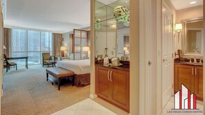 A hotel room with a large bed, a desk, a chair, a dining table, and a view of the city. - 11th Floor Luxurious Suite | Strip & F1 Views (Las Vegas)