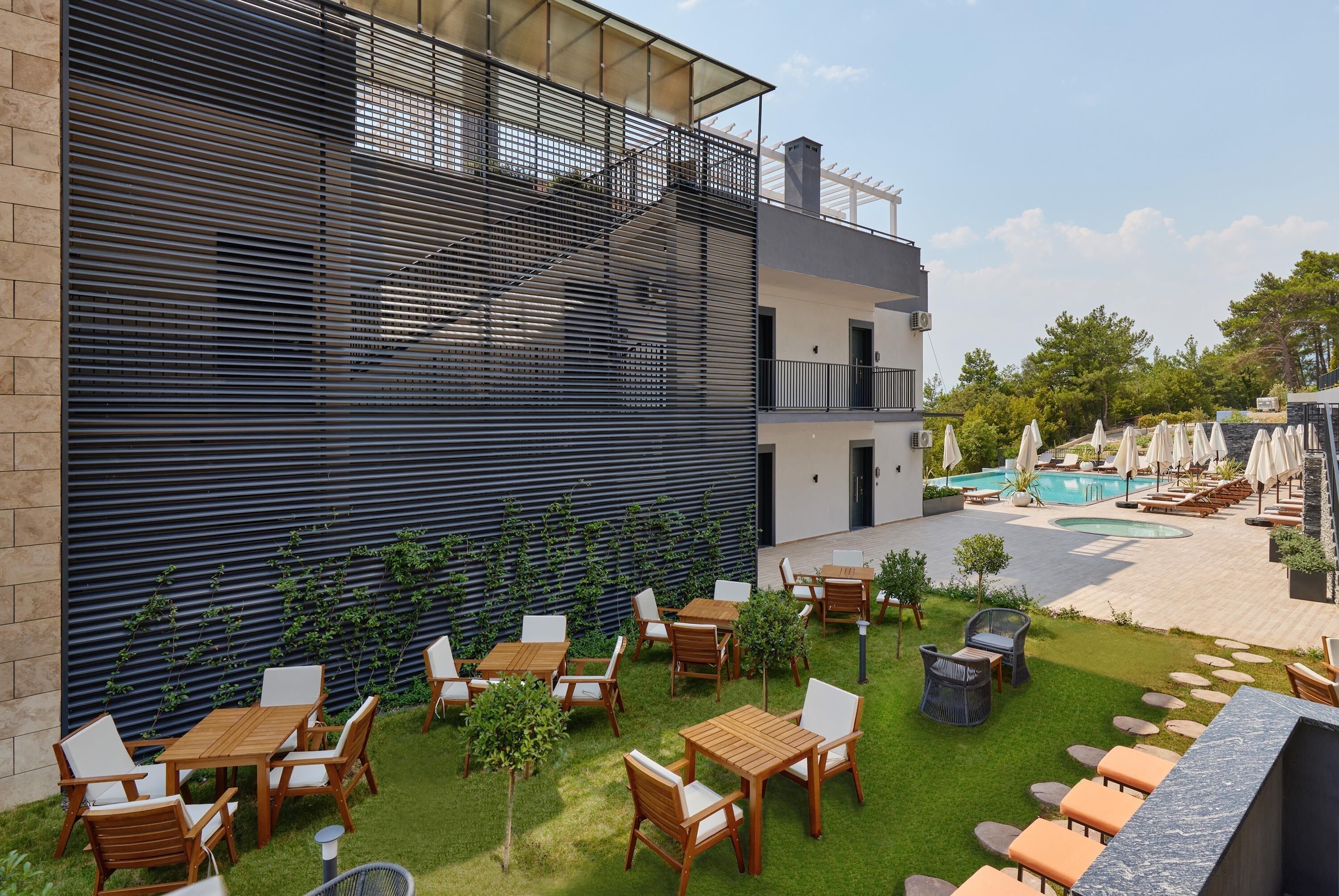 Eine moderne Außenpatio mit Holztischen und -stühlen, einem Swimmingpool und einem gepflasterten Weg.