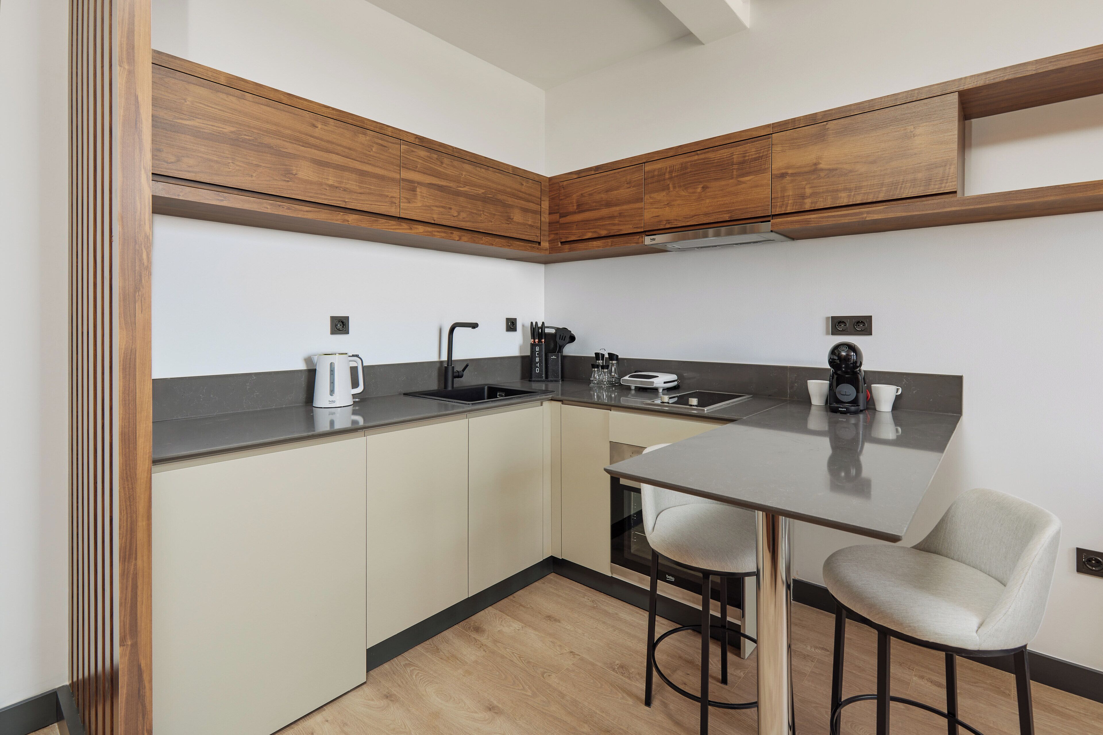A modern kitchen with wooden cabinets, a stainless steel sink, and a bar stool.