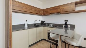 A modern kitchen with wooden cabinets, a stainless steel sink, and a bar stool.