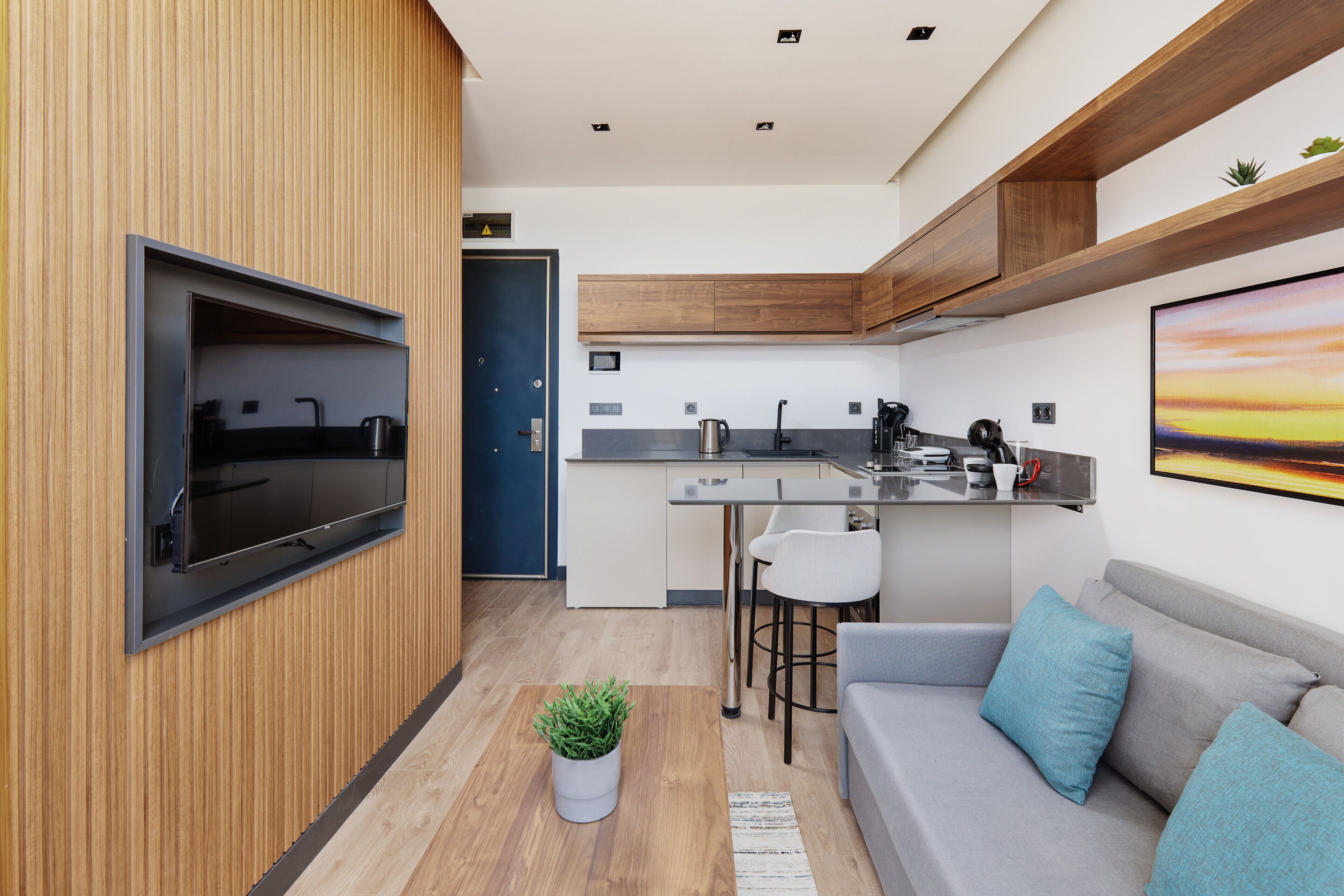Una cocina moderna con televisión integrada, armarios de madera y una zona de bar.