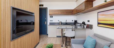 Una cocina moderna con televisión integrada, armarios de madera y una zona de bar.