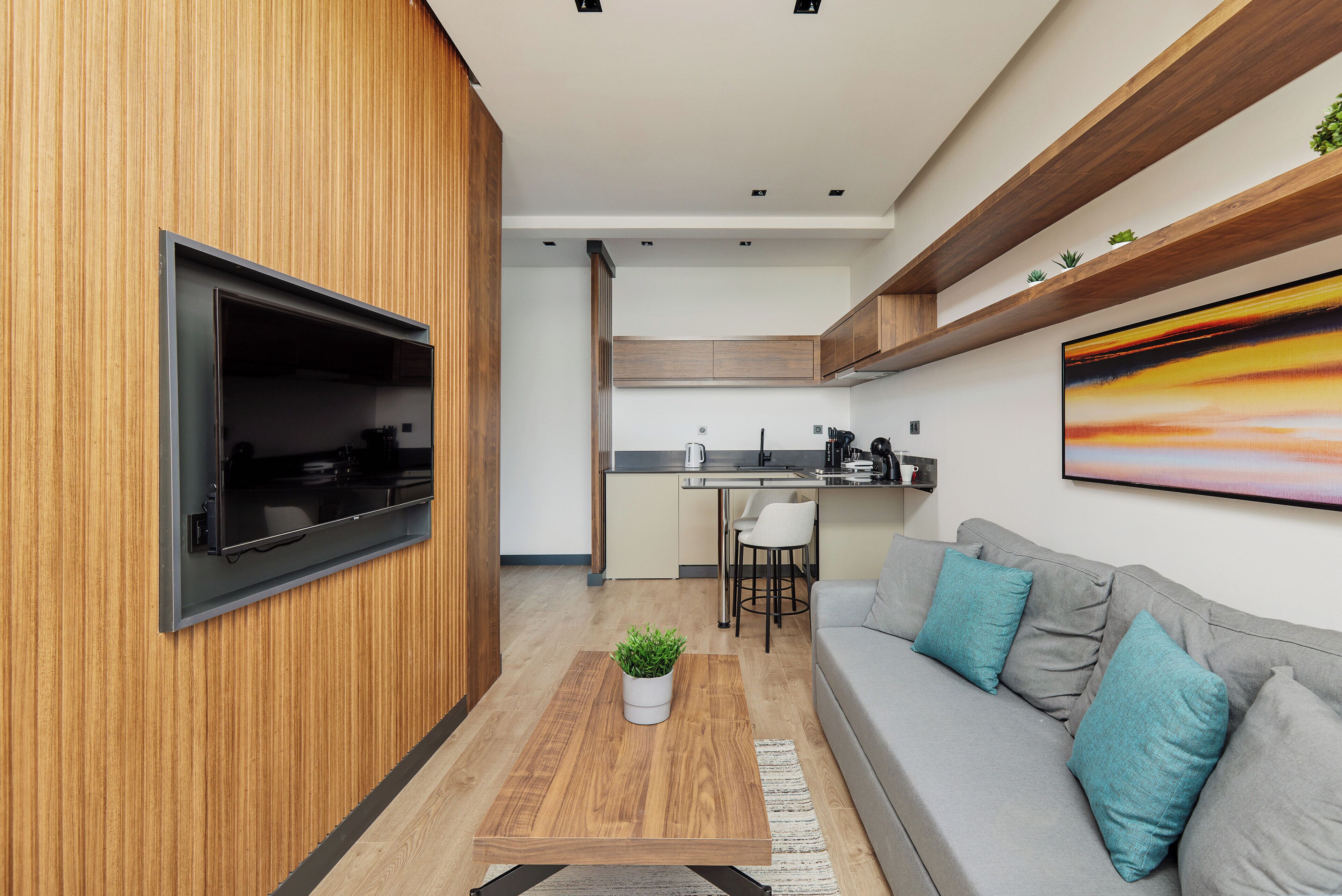 A modern kitchen with wooden cabinetry, a built-in oven, and a dining area with a white chair.