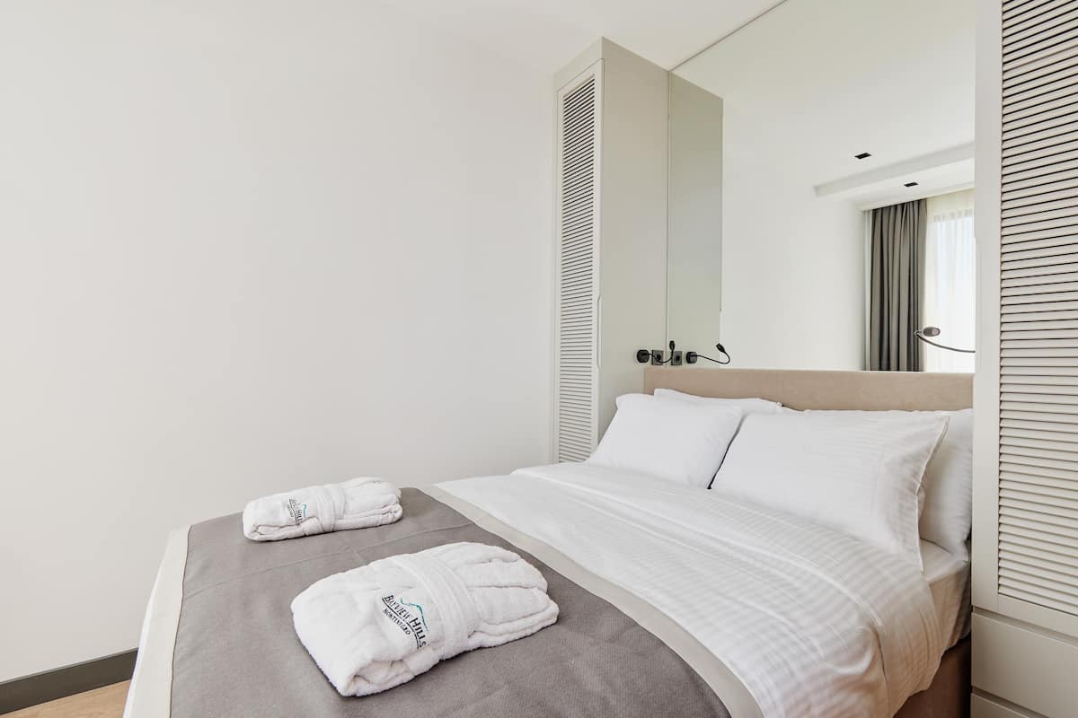 A hotel room with a bed, a large mirror, and two towels on the bed.