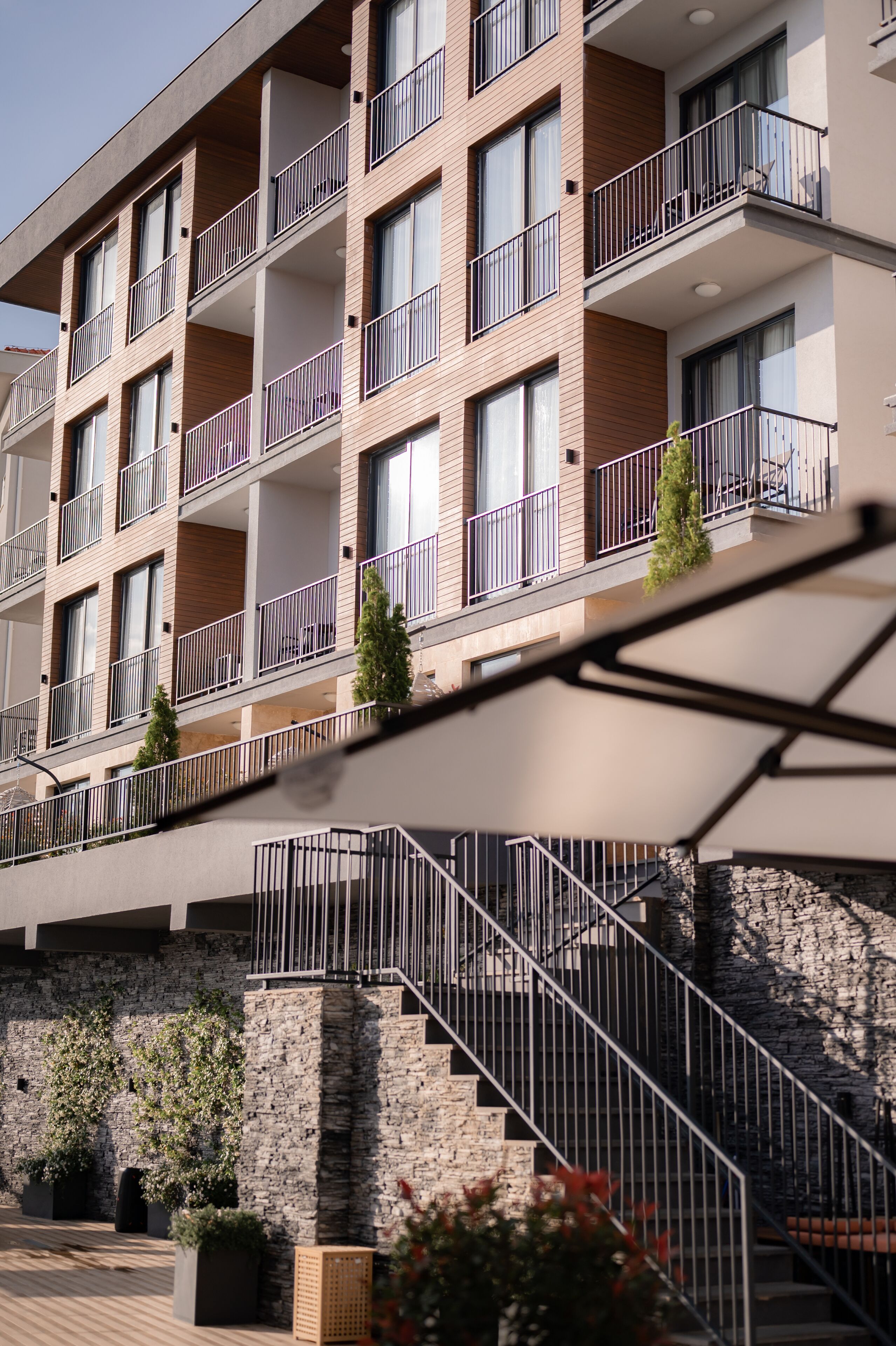 A multi-story hotel with balconies, a stone facade, and a staircase leading to the entrance.