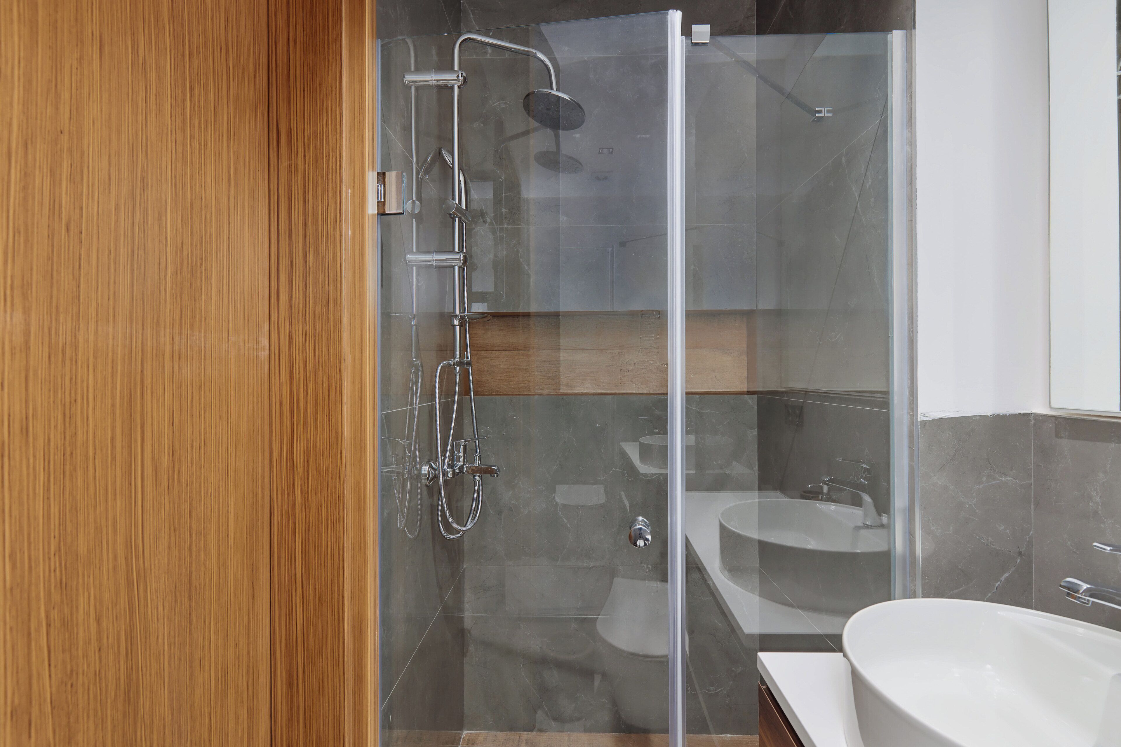 A modern bathroom with a glass-enclosed shower, a freestanding bathtub, and a wooden vanity.