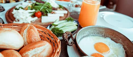A breakfast setting with bread, eggs, vegetables, and juice.