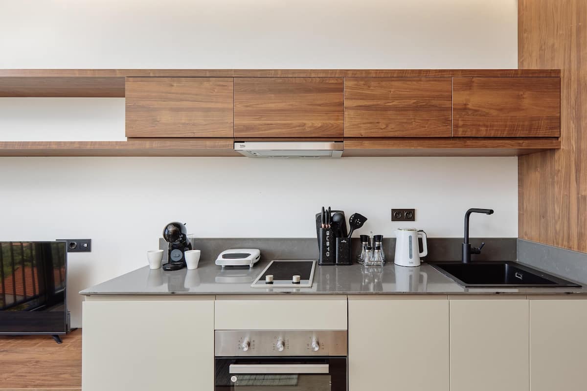 A modern kitchen with wooden cabinets, a stainless steel sink, and a built-in oven.
