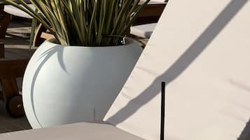A wooden table with a glass of pink drink, a white potted plant, and a white chair with a name card.