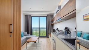 A modern apartment with a kitchen, dining area, and a balcony with a city view. - Bayview Hills Luxury Residences (Kotor)
