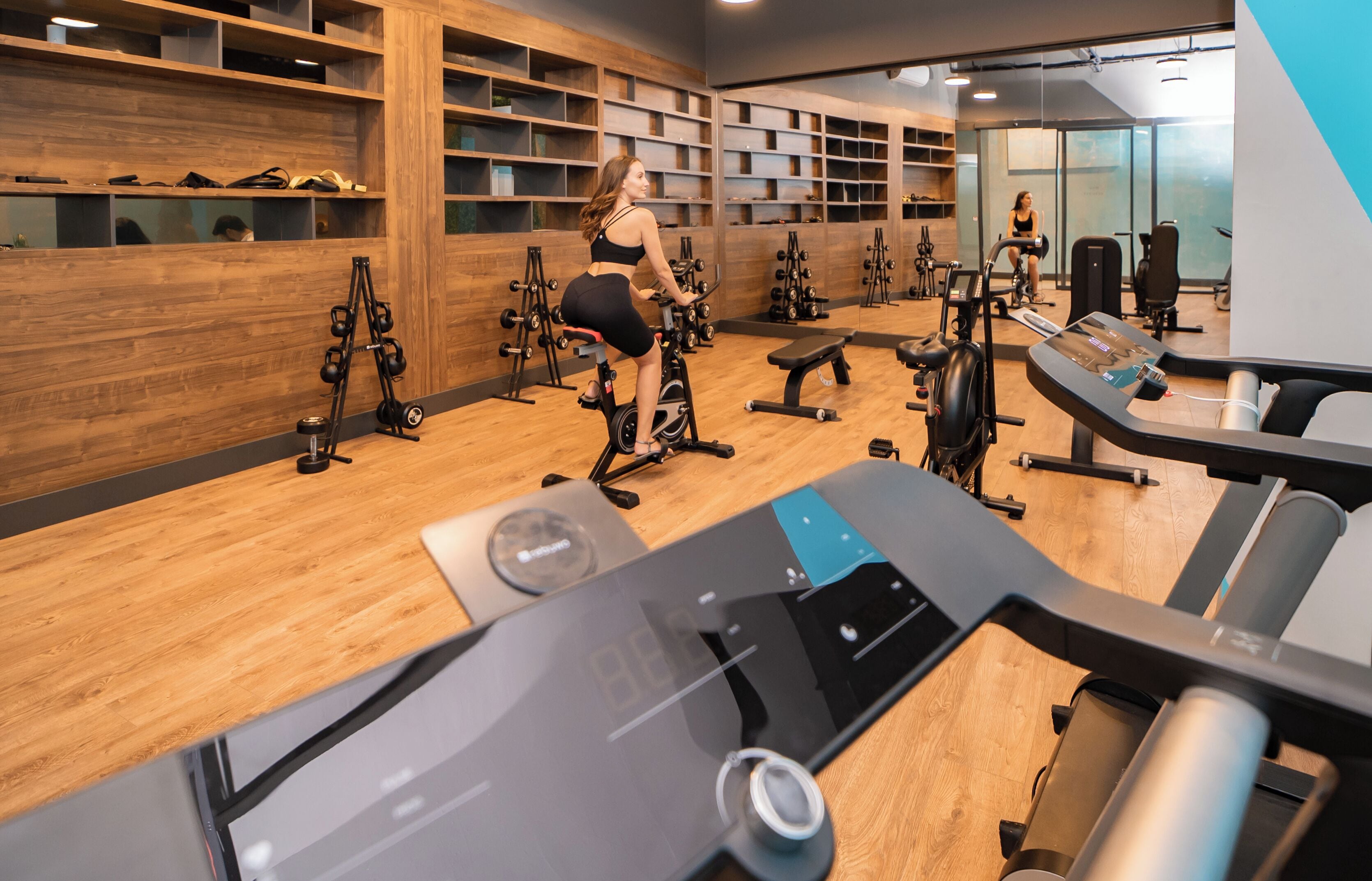 A gym with exercise equipment, wooden walls, and a mirrored wall.