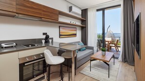 A modern kitchen with a dining area, a sofa, and a balcony with a view. - Bayview Hills Luxury Residences (Kotor)