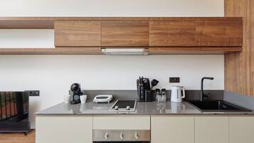 Una cocina moderna con armarios de madera, un lavamanos de acero inoxidable y un horno empotrado.