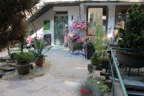 Un jardin agrémenté de plantes en pot, d’un banc en bois et d’un portail en métal.