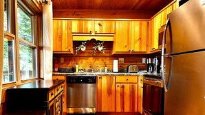 Cucina con mobili in legno, elettrodomestici in acciaio inossidabile e una finestra.