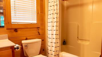 A wooden cabin bathroom with a toilet, sink, and bathtub.