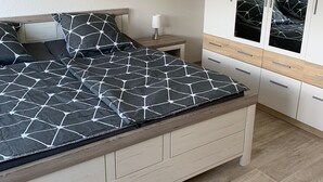 Een slaapkamer met een bed, nachtkastje en een kledingkast.