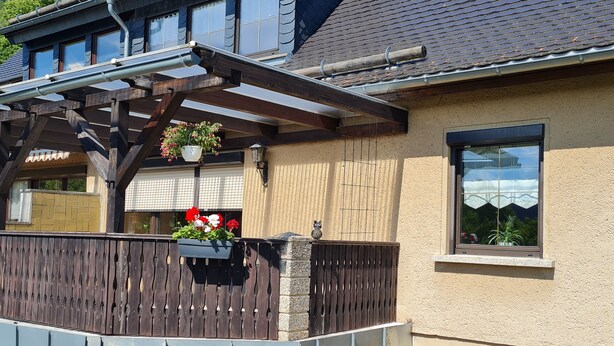 Een huis met een houten balkon, een raam met uitzicht en een bloempot.