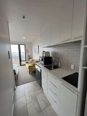 A modern kitchen with white cabinets, a black toaster, and a view to the outside.