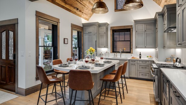 Una cocina moderna con una isla central, taburetes de bar y una mesa de comedor para seis comensales.