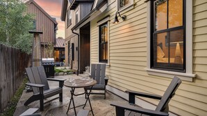 Un patio al aire libre con mesa y sillas, una parrilla y una valla de madera.