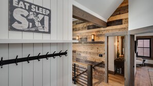 Un interior moderno con vigas de madera a la vista, una escalera y un letrero en la pared que dice 'EAT SLEEP SM'.