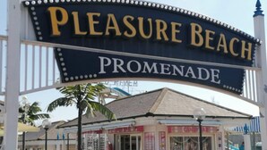 A sign for 'Pleasure Beach Promenade' with a kiosk in the foreground. - Beach Apartment With Garden (Skegness)