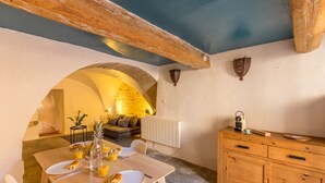 Un rincón comedor acogedor con una mesa de madera dispuesta para el desayuno, un arco de piedra y un mueble de madera rústica.