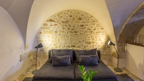 Una habitación acogedora con pared de piedra, dos sofás oscuros y dos lámparas de pie.