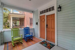 A porch with two chairs, a door, and a window overlooking a house. - Contemporary Apartment - 5 Min To TIAA Bank Field! (Jacksonville)