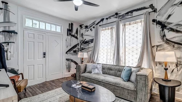 A modern living room with a sofa, coffee table, and a ceiling fan. - Contemporary Apartment - 5 Min To TIAA Bank Field! (Jacksonville)