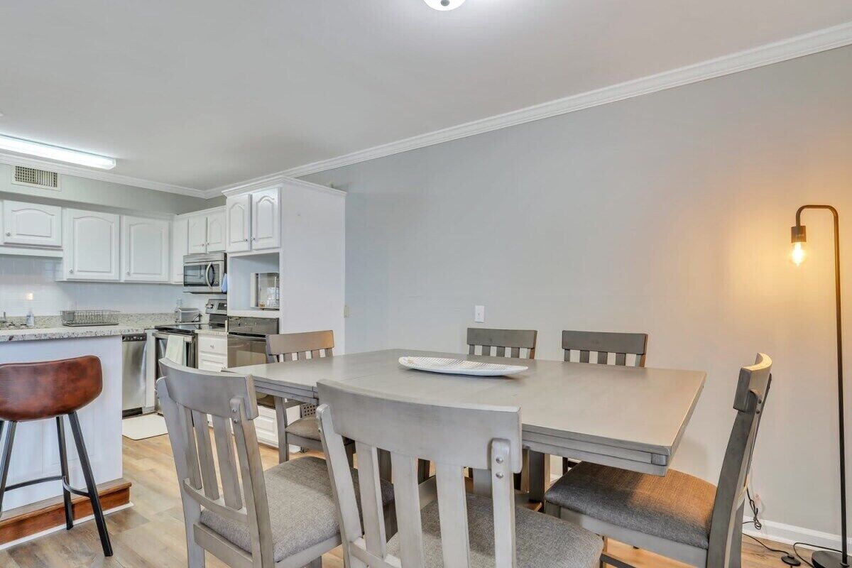 A modern kitchen with white cabinets, a dining table, and chairs.