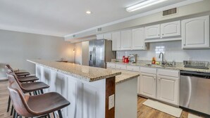 A modern kitchen with white cabinets, stainless steel appliances, and a granite countertop.