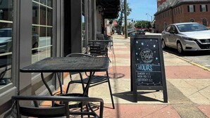 An outdoor seating area with tables and chairs, a signboard with the Boro Bagel Company logo, and a clear blue sky.