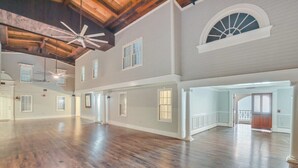 A spacious interior with high ceilings, wooden floors, and multiple windows.