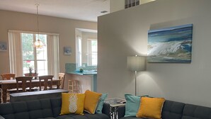 A living room with two dark sofas, a glass coffee table, and a dining area with a table and chairs. - Beautiful, Pet-Friendly Coastal Getaway (Palm Coast)