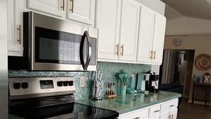 A modern kitchen with white cabinets, stainless steel appliances, and a green backsplash. - Beautiful, Pet-Friendly Coastal Getaway (Palm Coast)
