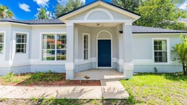A single-story house with a front porch, a dark blue door, and a small garden area. - Beautiful, Pet-Friendly Coastal Getaway (Palm Coast)