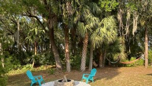 A garden with two turquoise chairs, a fire pit, and a hammock. - Beautiful, Pet-Friendly Coastal Getaway (Palm Coast)