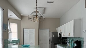 A modern kitchen with white cabinets, a stainless steel refrigerator, and a green backsplash. - Beautiful, Pet-Friendly Coastal Getaway (Palm Coast)